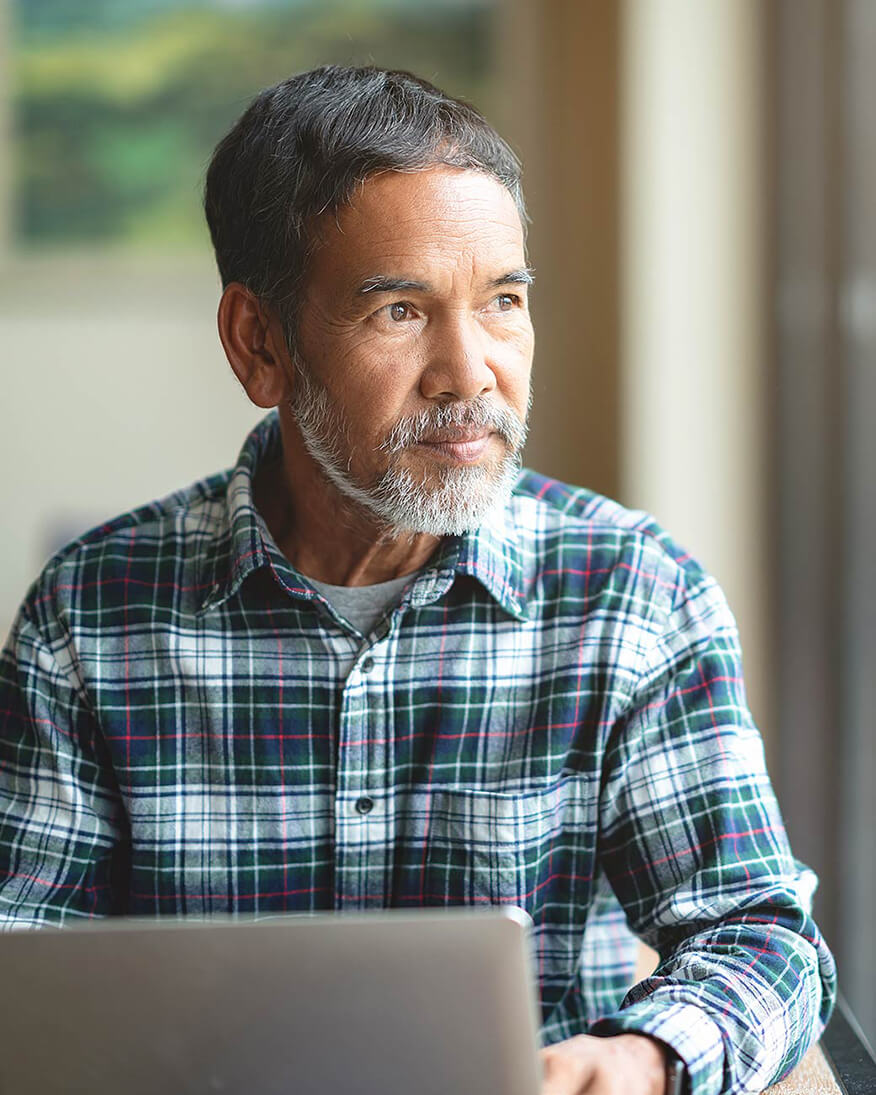 Man squinting at a laptop screen — a common early sign of cataracts