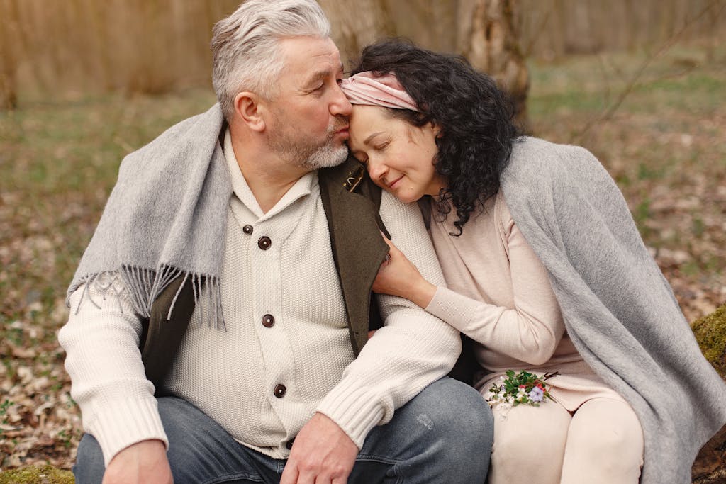 Senior couple enjoying a warm embrace in a serene autumn park, showcasing love and companionship.